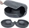 A hand is shown opening a zippered felt cat bed. The bed is dark gray and shaped like a donut tunnel. Produktbild-Vorschau