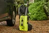 A Ryobi pressure washer is placed on a gravel surface next to a dark-colored vehicle and green bushes. Produktbild-Vorschau