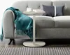 A side table next to a sofa with a throw blanket and pillows. Voir les images du produit