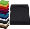 A stack of folded fitted sheets in various colors is shown on the left, and a single black fitted sheet is displayed on a flat surface on the right. Produktbild-Vorschau