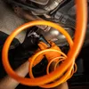 A person wearing orange gloves is using a pneumatic cutting tool on a car's exhaust system. Produktbild-Vorschau