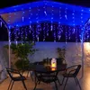 An outdoor patio at night, decorated with blue icicle string lights. Produktbild-Vorschau