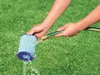 Hands cleaning a pool filter with a garden hose on a grassy lawn. Produktbild-Vorschau