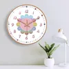 A clock on a wall with a plant and lamp in the foreground. Produktbild-Vorschau