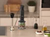 A black immersion blender set with attachments and ingredients on a kitchen counter. Anteprima dell’immagine prodotto