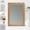 A gold-framed mirror is displayed on a white surface, with a vase and dried flowers to the right. The left side of the image shows product details and accessories. Produktbild-Vorschau