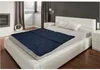 A bedroom with a bed made up with a navy blue blanket. Produktbild-Vorschau