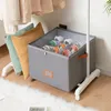 A shoe organizer box filled with shoes, placed on a wooden floor next to pillows and a clothing rack. Náhled obrázku produktu