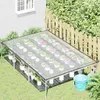 A greenhouse structure with plants in pots, set up in a backyard next to a wooden fence and a house. Produktbild-Vorschau