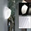 A collage of images showing a white outdoor wall light, a close-up of the light's illuminated interior, and a detail of its mounting structure. Náhľad obrázku produktu