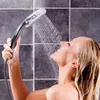 A woman is taking a shower and holding a shower head to her face. Anteprima dell’immagine prodotto