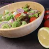 A salad in a wooden bowl with tomatoes and lemon on the side. Produktbild-Vorschau
