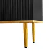 A close-up view of the bottom section of a black cabinet with fluted doors, supported by golden tapered legs. Produktbild-Vorschau
