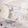 A close-up view of a transparent curtain with a floral pattern draped over a table setting with plates and a vase. Produktbild-Vorschau