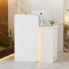 A modern white reception desk with integrated LED lighting, placed in a well-lit interior space with plants and marble accents. Náhľad obrázku produktu