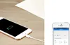 A smartphone is charging on a wooden surface next to a white sheet of paper. A second smartphone screen is visible on the right, displaying a grid of numbers and text. Produktbild-Vorschau