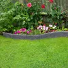 A garden bed with flowers and a stone-look plastic border, set against a lawn and wooden fence. Produktbild-Vorschau