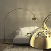 A modern living room with a white sofa and a gold arc floor lamp. Náhled obrázku produktu