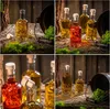 A collage of four images showing glass bottles with corks, filled with various colored liquids, set in a rustic, natural environment with moss and wood. Voir les images du produit