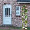 A multi-tiered plant stand with potted plants in front of a brick house with a white door and window. Podgląd zdjęcia produktu