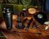 A collection of black barware tools arranged on a wooden table with a green tiled backsplash. Voir les images du produit
