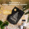 A black paper bag with a Christmas tree design and text, placed on a wooden surface with scattered artificial snow and Christmas decorations. Anteprima dell’immagine prodotto