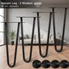 Four black hairpin legs are displayed in a room setting with a sofa in the background. There are also four black circular floor protectors shown in the foreground. Anteprima dell’immagine prodotto