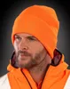 Close-up of a man wearing an orange beanie and jacket. Anteprima dell’immagine prodotto