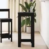 A black wooden bar table with a plant on it, next to a bar stool, in a room with light-colored curtains and floor. Produktbild-Vorschau