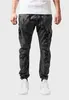A person is shown from the waist down, wearing camouflage cargo pants and white sneakers. Produktbild-Vorschau