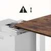A close-up view of a desk frame with a wooden tabletop being placed on it, next to a stack of books. Anteprima dell’immagine prodotto