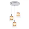 A modern pendant light fixture with three glass shades containing decorative elements. Produktbild-Vorschau