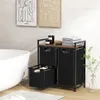 A bathroom scene with a freestanding laundry sorter, bathtub, and artwork on the wall. Produktbild-Vorschau