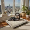 A dog is resting on a plush dog bed in front of a large window with a city view. Anteprima dell’immagine prodotto