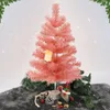 A pink artificial Christmas tree with decorations on a gray surface, with a white snowy background. Anteprima dell’immagine prodotto