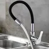 A close-up shot of a modern kitchen faucet with a flexible black hose, dispensing water into a stainless steel sink. Náhľad obrázku produktu