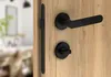 A close-up view of a black door handle set on a light wood door. Produktbild-Vorschau