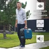 A man is carrying a portable generator in a yard with trees and a fence in the background. There are marketing graphics on the right side of the image. Podgląd zdjęcia produktu