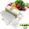 A multi-functional grater with a storage container and various attachments, surrounded by fresh vegetables. Produktbild-Vorschau