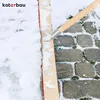 A broom is being used to clear snow from a cobblestone path. Produktbild-Vorschau