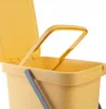 A close-up view of the top portion of a yellow plastic trash can with a lid and handle. Podgląd zdjęcia produktu