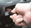 A hand is inserting a plug into a car's power outlet. Produktbild-Vorschau