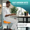 A man sitting on an orange stool while using a laptop in an office setting. Produktbild-Vorschau