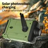 A green and black emergency radio with a hand crank, placed on rocks outdoors with blurred foliage in the background. Produktbild-Vorschau