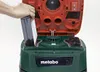A person's hand is inserting a filter into a green and red Metabo vacuum cleaner. Náhľad obrázku produktu