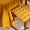 A close-up of a yellow tablecloth draped over a table and a yellow chair cushion on a wooden chair. Anteprima dell’immagine prodotto