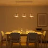 A dining table with chairs and a pendant light fixture above. Produktbild-Vorschau