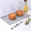 Two round pastries and two small cake rolls are displayed on a black cooling rack against a marble-like background. Produktbild-Vorschau