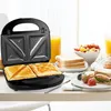 A sandwich maker with toasted sandwiches and breakfast items on a table. Produktbild-Vorschau