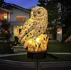 A solar-powered owl garden stake is illuminated at dusk in front of a house. Náhled obrázku produktu